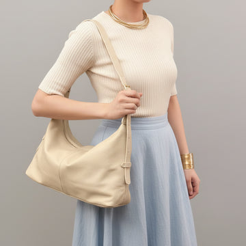 Woman wearing the Ivory Elettra bag on her shoulder in cream