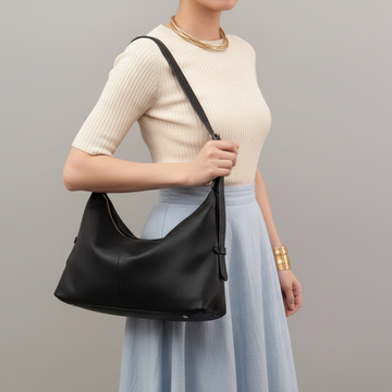 Woman wearing the Black Elettra bag on her shoulder in cream