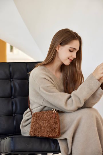 Woman wearing the Chocolate Zita crossbody bag, seated in a cream sweater