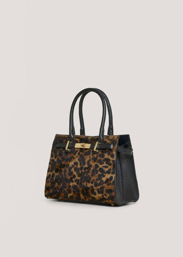 Leonora leopard calf hair bag at a three-quarter angle, showing the black Togo leather side panel and 15 cm depth