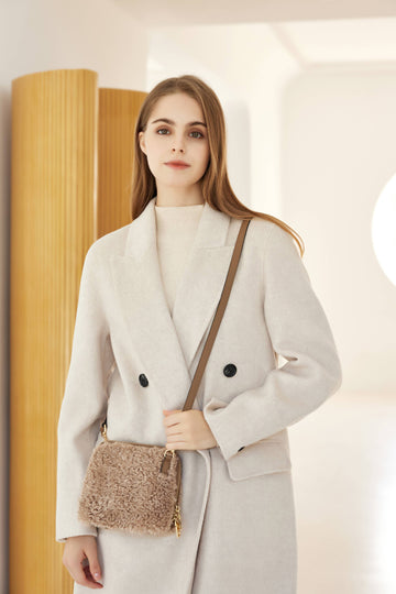 Woman wearing the Light Taupe Zita crossbody bag in a cream coat