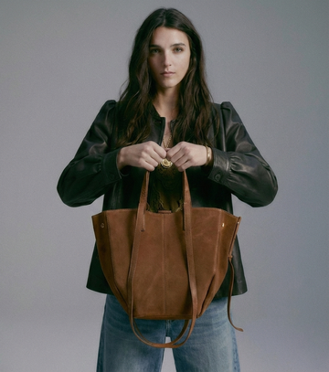Woman holding the Chocolate Liviana tote bag against her torso