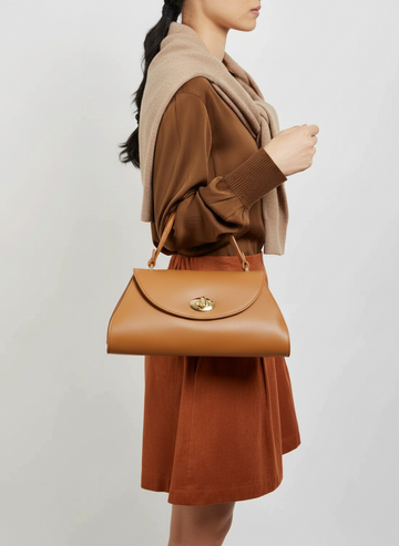 Woman carrying the Tan Aveline flap bag by its top handle