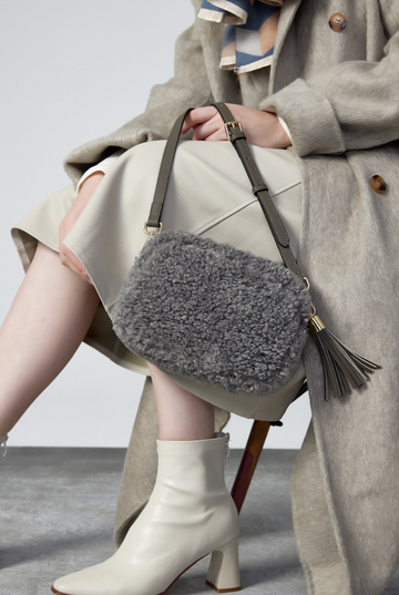 Woman wearing the Dover Grey Georgette camera bag with a tassel, studio shot