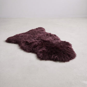 Aubergine single sheepskin rug laid on a pale floor