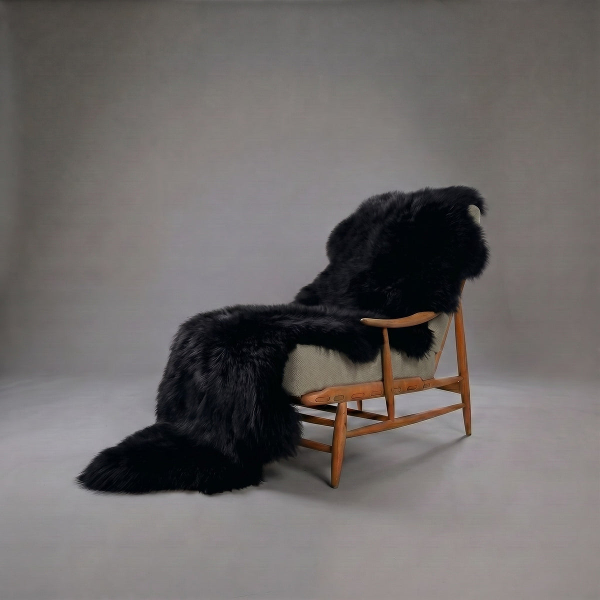 Black double New Zealand sheepskin rug and throw draped over a wooden armchair