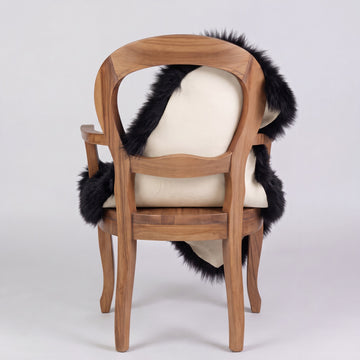 Black sheepskin rug over the back of a chair showing the cream suede underside