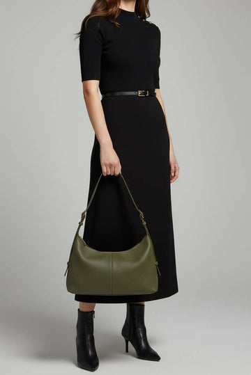 Woman wearing the Dark Olive Elettra bag on her shoulder in a black dress