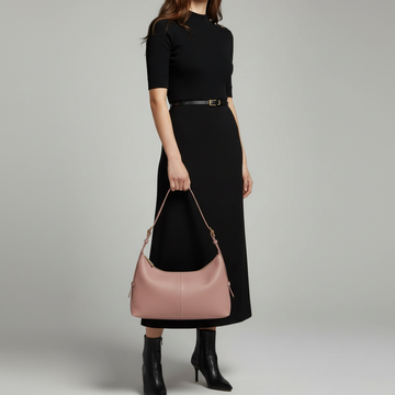 Woman wearing the Dusty Rose Elettra bag on her shoulder in a black dress