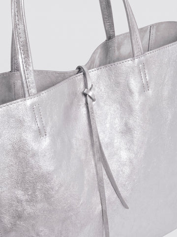 Carlotta oversized leather tote by Clemés in Silver metallic leather, close-up of the top edge with rolled handles and knotted leather tie