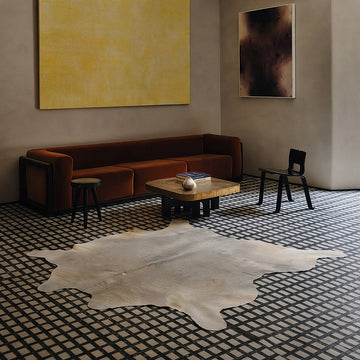 Pale grey cowhide rug in a moody tile-floor living room