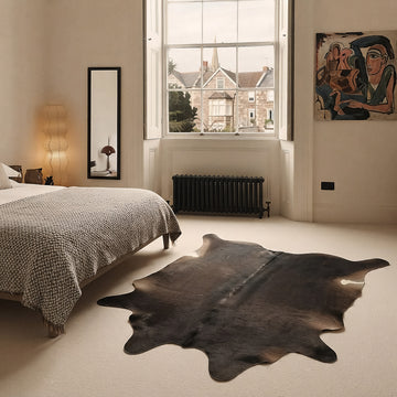 Espresso solid cowhide rug styled on the floor of an elegant Georgian bedroom