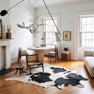 Black and white cowhide rug in a living room with black leather chesterfield