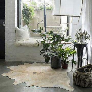 Ivory speckled cowhide rug styled on the floor of a boho window-seat nook