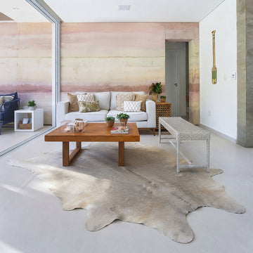 Pale grey cowhide rug in a soft blush-pink living room