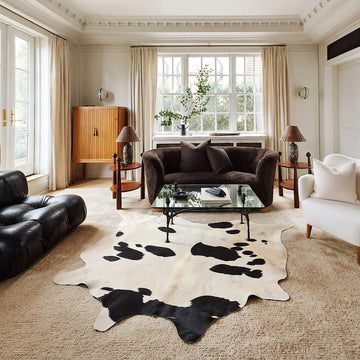 Black and white cowhide rug in a living room with black leather chesterfield
