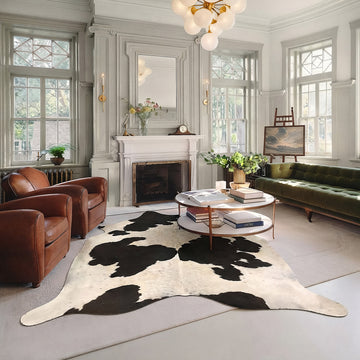 Speckled black and white cowhide rug styled on the floor of an elegant chesterfield living room