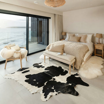 Black and white cowhide rug styled on the floor of a coastal ocean-view bedroom
