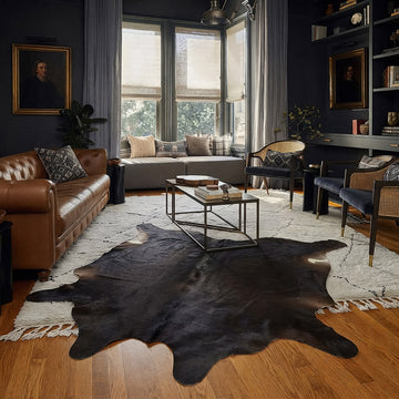 Espresso solid cowhide rug styled on the floor of a dark academia living room