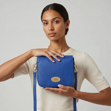 Close-up of the Royal Blue Chiara crossbody bag and gold turn-lock clasp held in both hands
