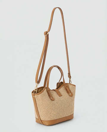 Sorrento raffia tote at three-quarter angle with detachable crossbody strap, light grey studio background