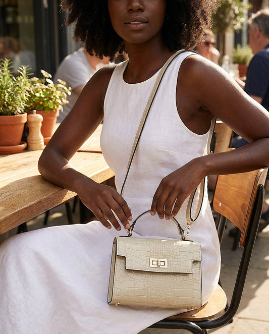 Woman with the Ivory Margot Croc crossbody bag at a sunlit café terrace