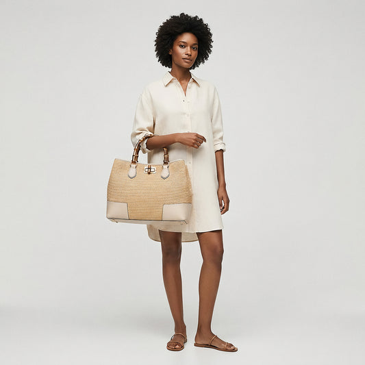 Model holding the Oyster Ginevra Bamboo-Handle Raffia Bag by Clemés by its top handle, studio shot