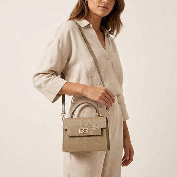 Model carrying the Light Taupe Margot Croc crossbody bag on her shoulder, studio shot