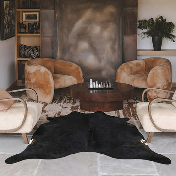 Black cowhide rug in a living room with brown velvet armchairs