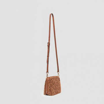 Zita faux shearling crossbody bag in tan, angled view on a light grey studio background