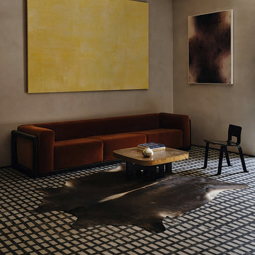 Dark chocolate cowhide rug in a moody tile-floor living room