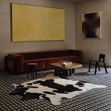 Black and white cowhide rug styled on the floor of a moody tile-floor living room