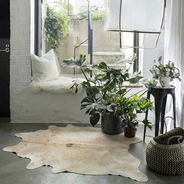 Pale cream cowhide rug in a boho window-seat nook