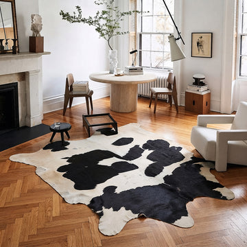Black and white cowhide rug in a herringbone-floored dining nook