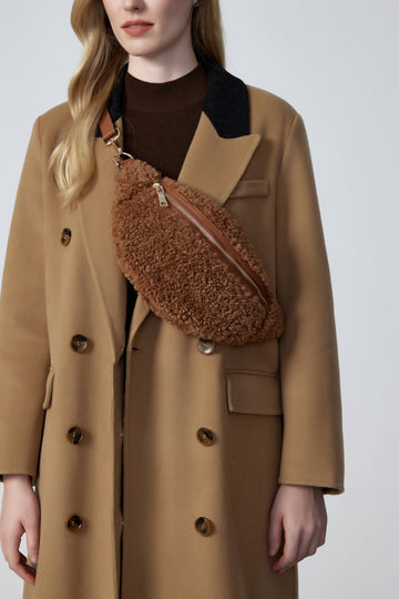 Woman wearing the Taupe Nevina bum bag in a camel coat