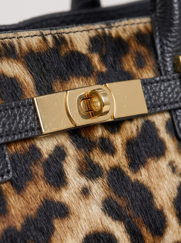 Close-up of the Leonora calf hair bag's gold-tone turn-lock set against the real leopard-print calf hair and black Togo leather