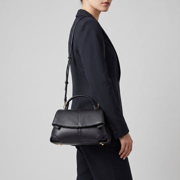 Model carrying the Black Fiorella leather baguette on her shoulder, studio shot