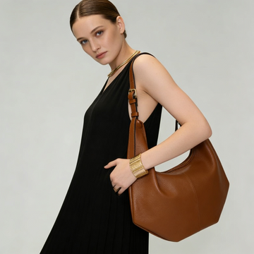 Woman wearing the Tan Ludovica hobo bag on her shoulder in a black dress