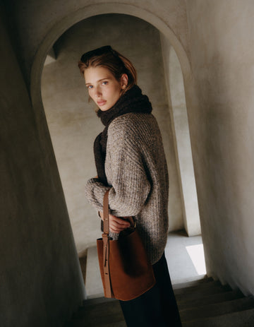 Woman carrying the Chocolate Serena bucket bag in a tweed coat