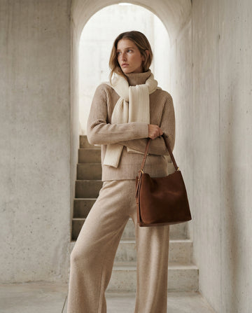 Woman wearing the Tan Serena bucket bag on her shoulder in a cream co-ord