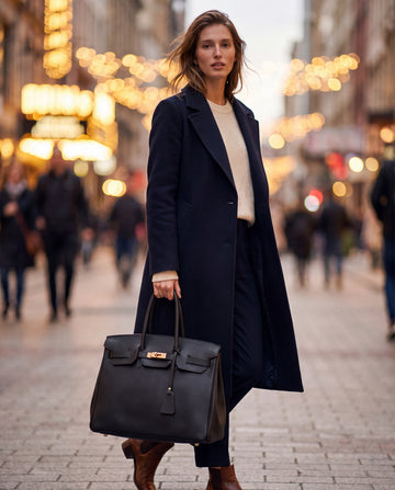 Woman carrying the Black Valentina tote on a city street at night