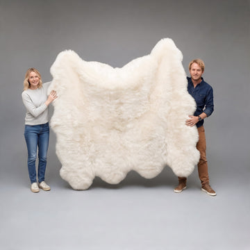 Couple holding up an Ivory Octo New Zealand sheepskin rug in a grey studio