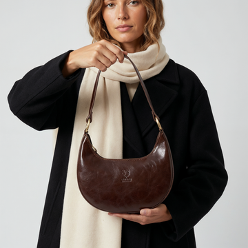Woman carrying the Chocolate Mezzaluna bag in a black coat and scarf
