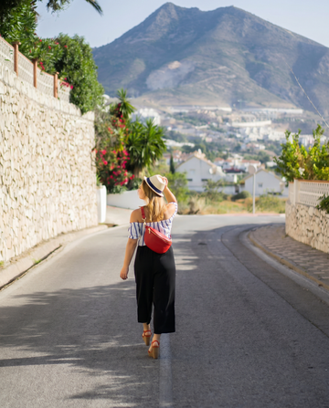 Romy Genuine Leather Crossbody Bum Bag in Red, worn crossbody by a woman exploring a European town street on a bright summer day