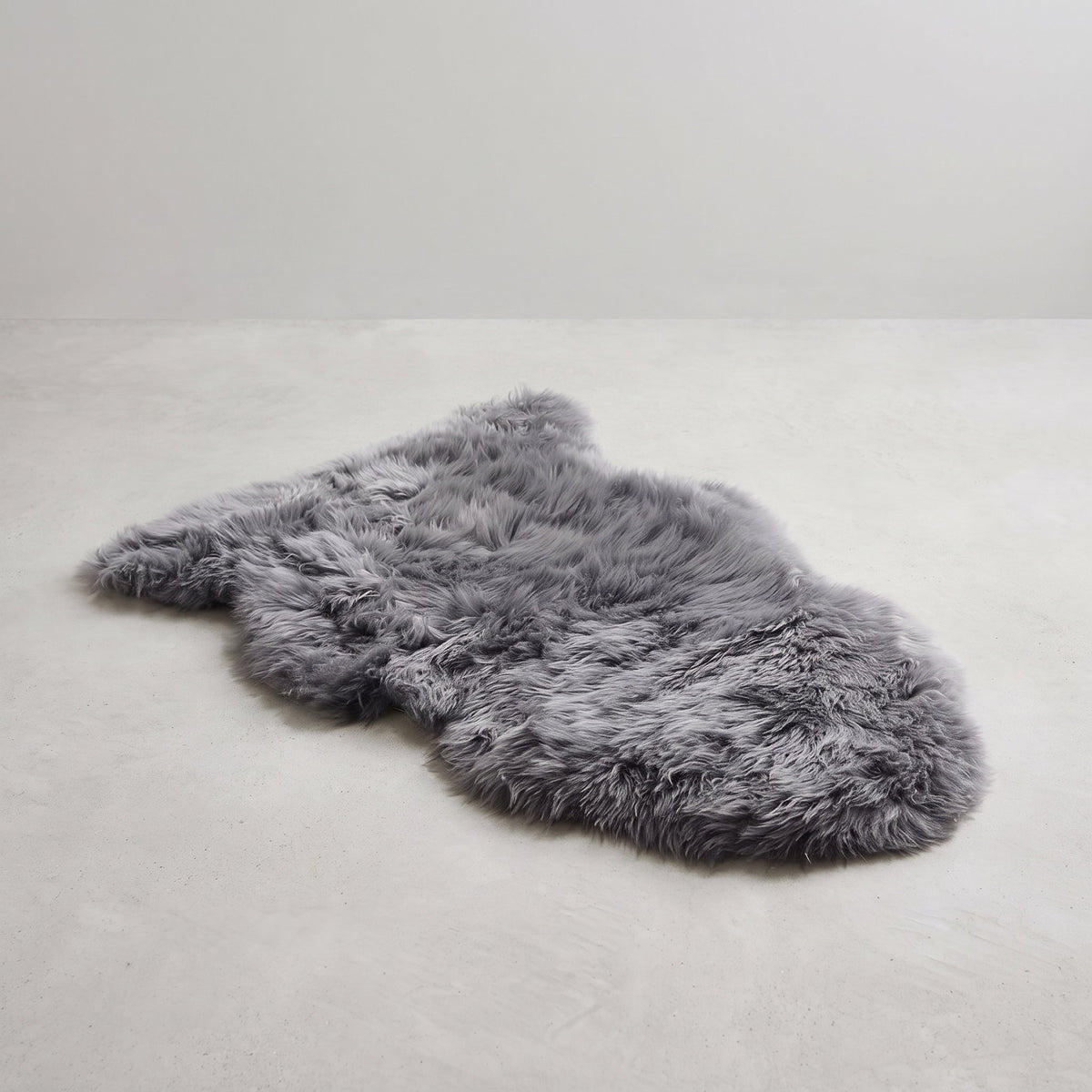 Grey single sheepskin rug laid flat on a pale grey floor