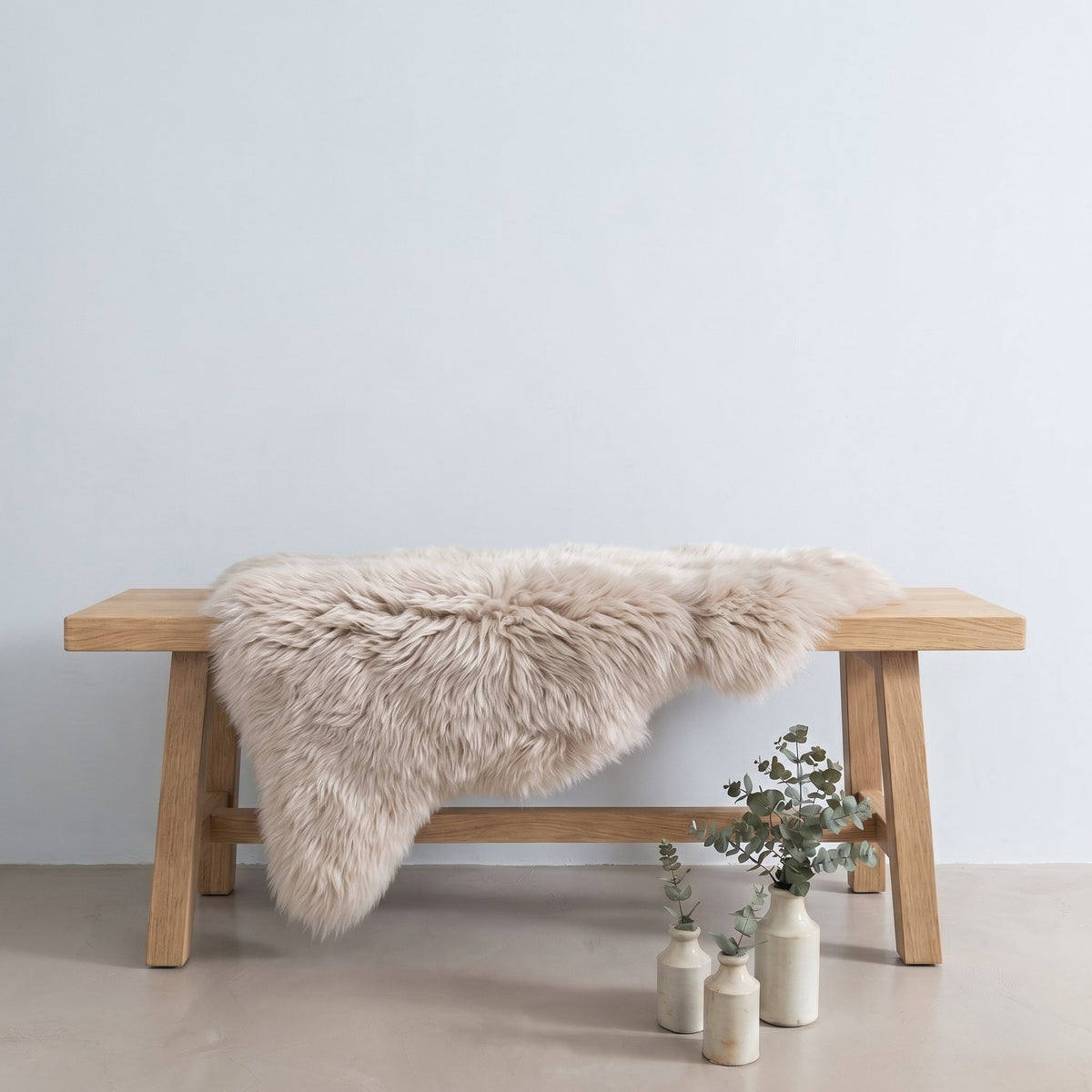 Oyster sheepskin rug draped over an oak bench in a minimal interior