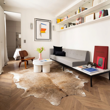Natural cowhide rug styled on the floor of an editorial interior room