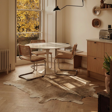 Caramel and ivory exotic printed cowhide rug styled on the floor of an editorial interior