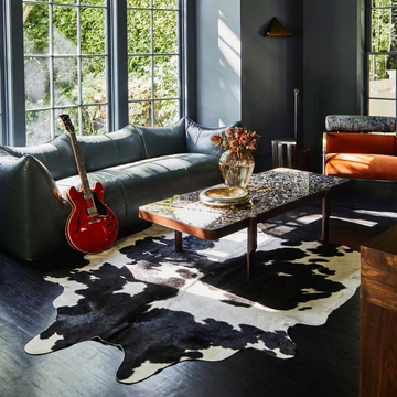 Caramel and ivory exotic printed cowhide rug styled on the floor of an editorial interior