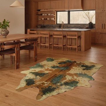 Acid-wash green and tan cowhide rug styled on the oak floor of a warm contemporary kitchen and dining room